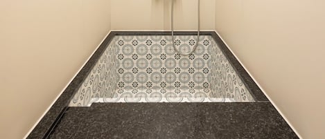 A small, enclosed shower area with a patterned floor and a single showerhead.