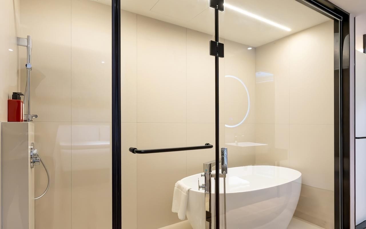 A modern bathroom with a glass shower enclosure, a white sink, and a glass door.