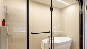 A modern bathroom with a glass shower enclosure, a white sink, and a glass door.