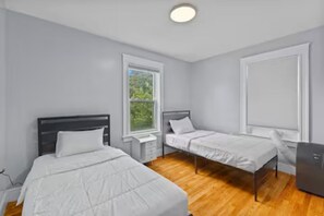 Una camera da letto con due letti singoli, un comodino, una scrivania e una finestra.