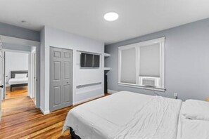 A bedroom with a bed, a window, and a door.