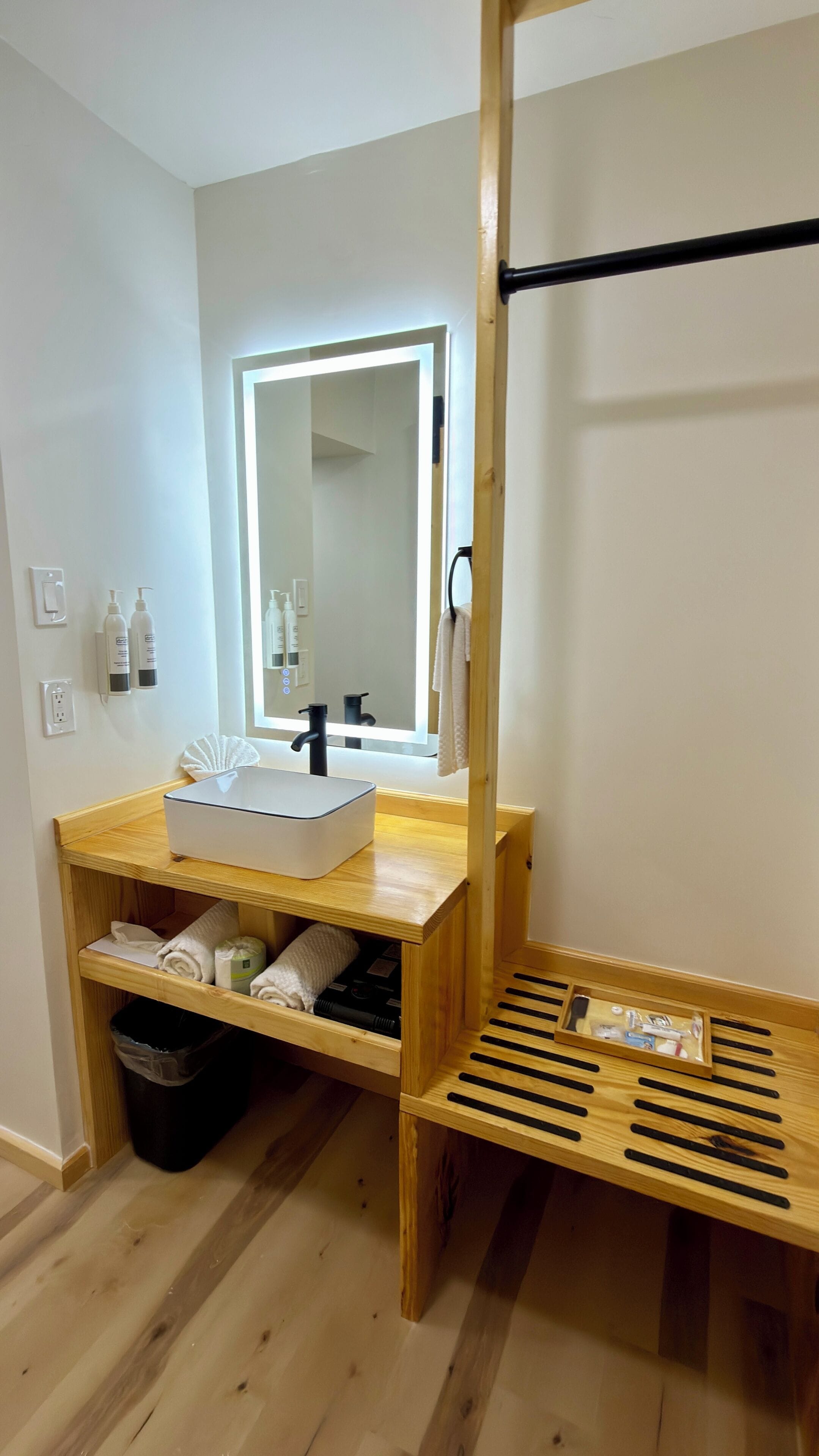 A bathroom with a wooden vanity, a mirror, a sink, and a towel rack.