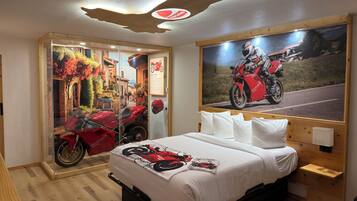 Une chambre à coucher avec un lit, une affiche de moto et une fenêtre donnant sur une moto rouge.