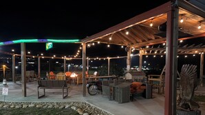 An outdoor patio with wooden furniture, string lights, and a stone border. - Motorcycle Inn (Kodak)