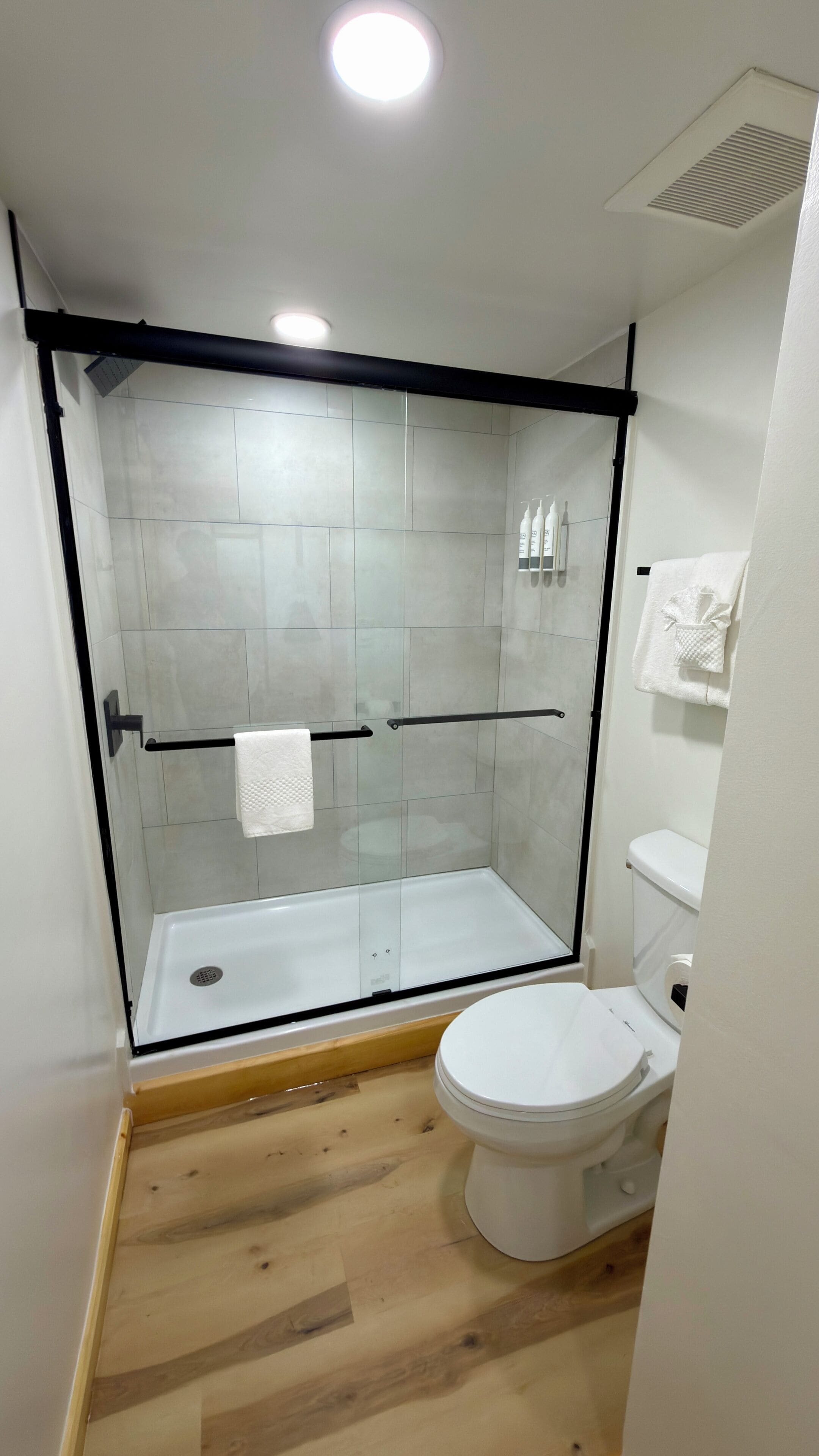 Un baño moderno con ducha de vidrio, inodoro y perchero para toallas.
