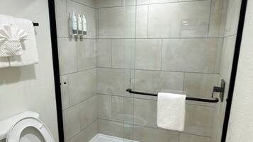 Een badkamer met toilet, een douchecabine en een handdoekhouder.