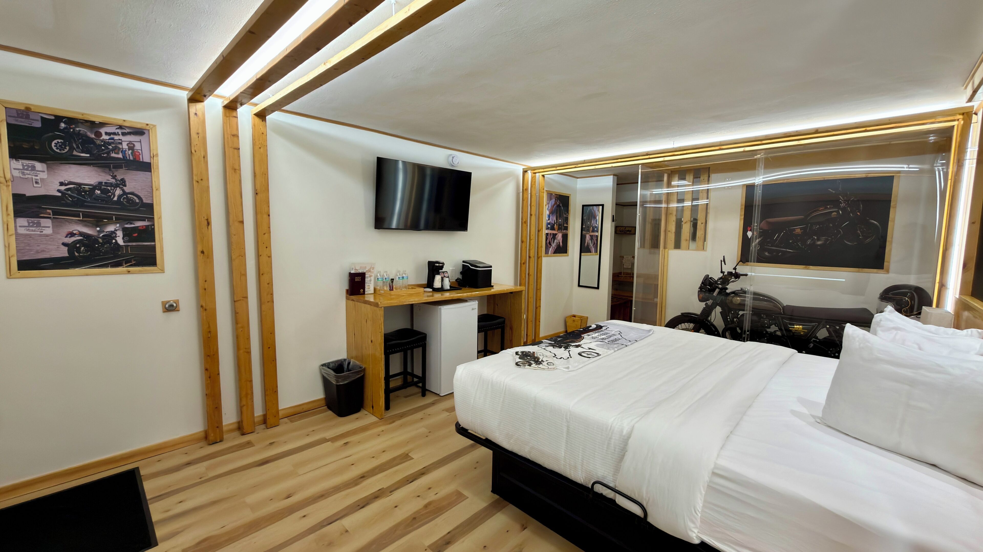 A bedroom with a bed, a desk, a TV, and motorcycle-themed decorations.