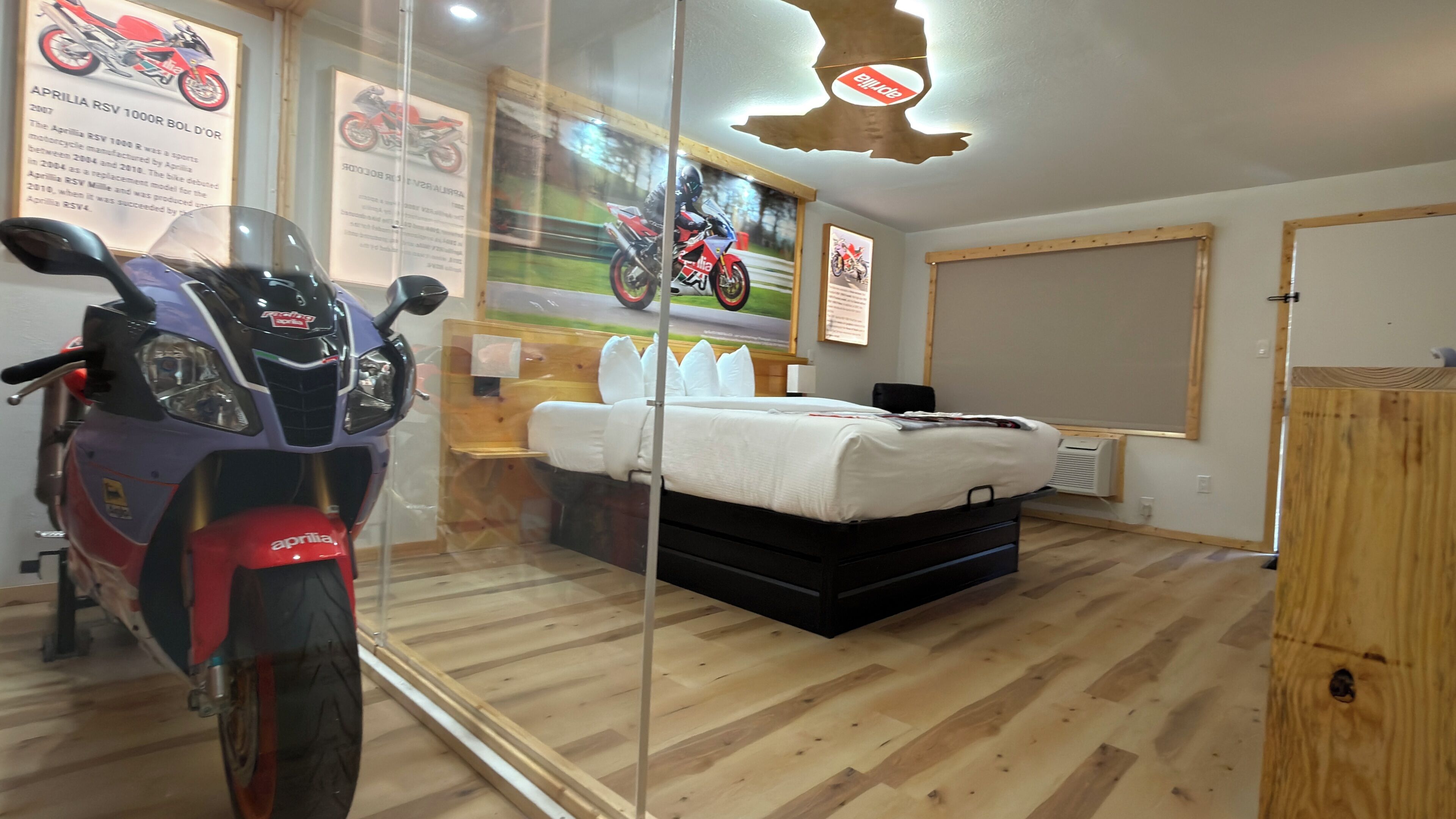 A room with a bed, a motorcycle, and a wooden cabinet.