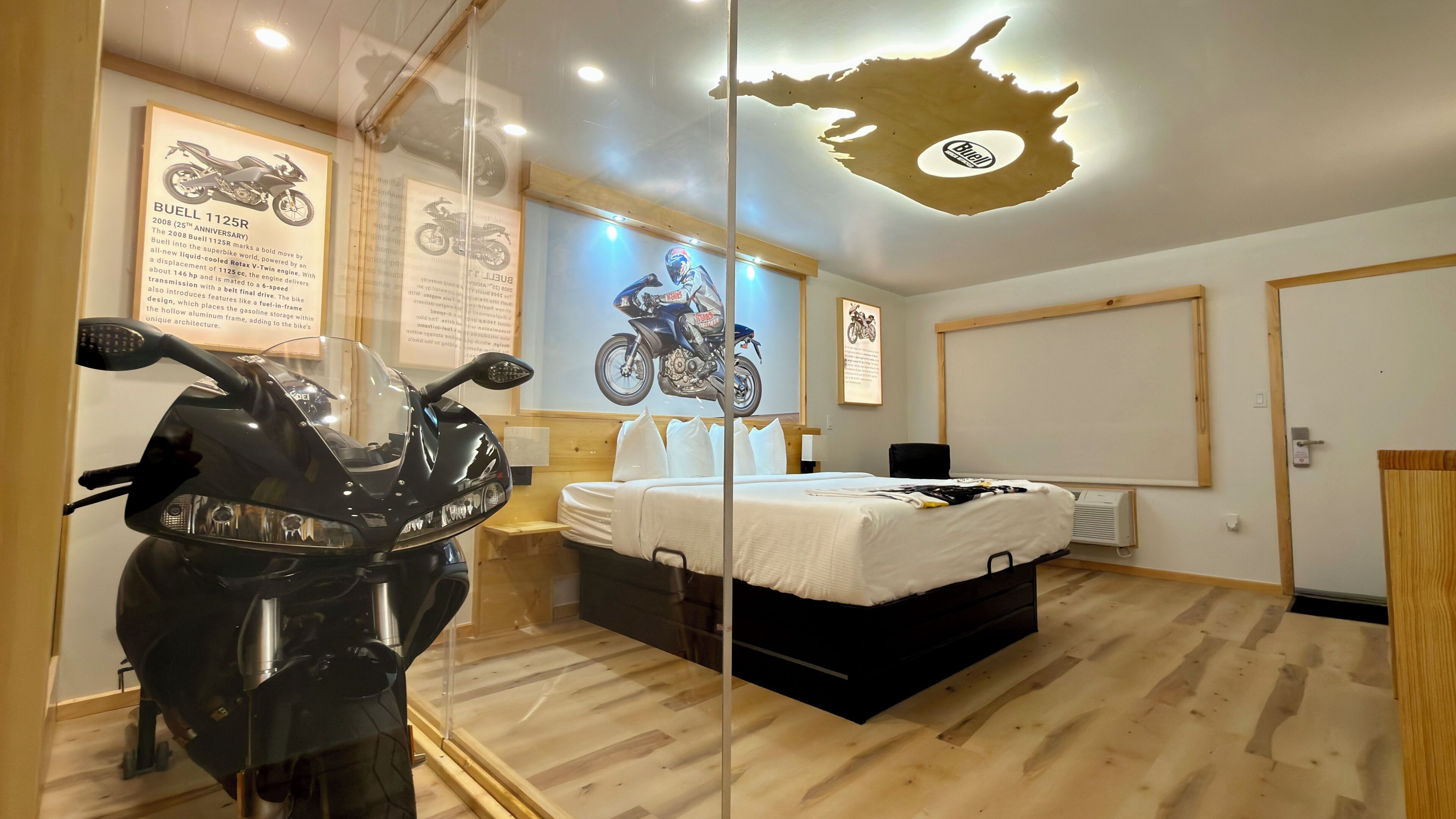 Ein Hotelzimmer mit einem Bett, einem Motorrad und einer Wand mit Motorradplakaten.