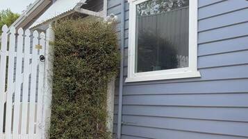 A house with a white picket fence, a potted plant, and a window.