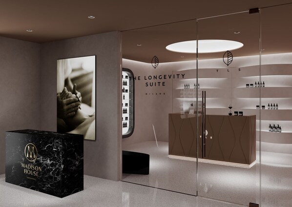 Un hall d’hôtel moderne avec un comptoir de réception en marbre, une grande photographie encadrée et une vitrine en verre présentant divers produits.