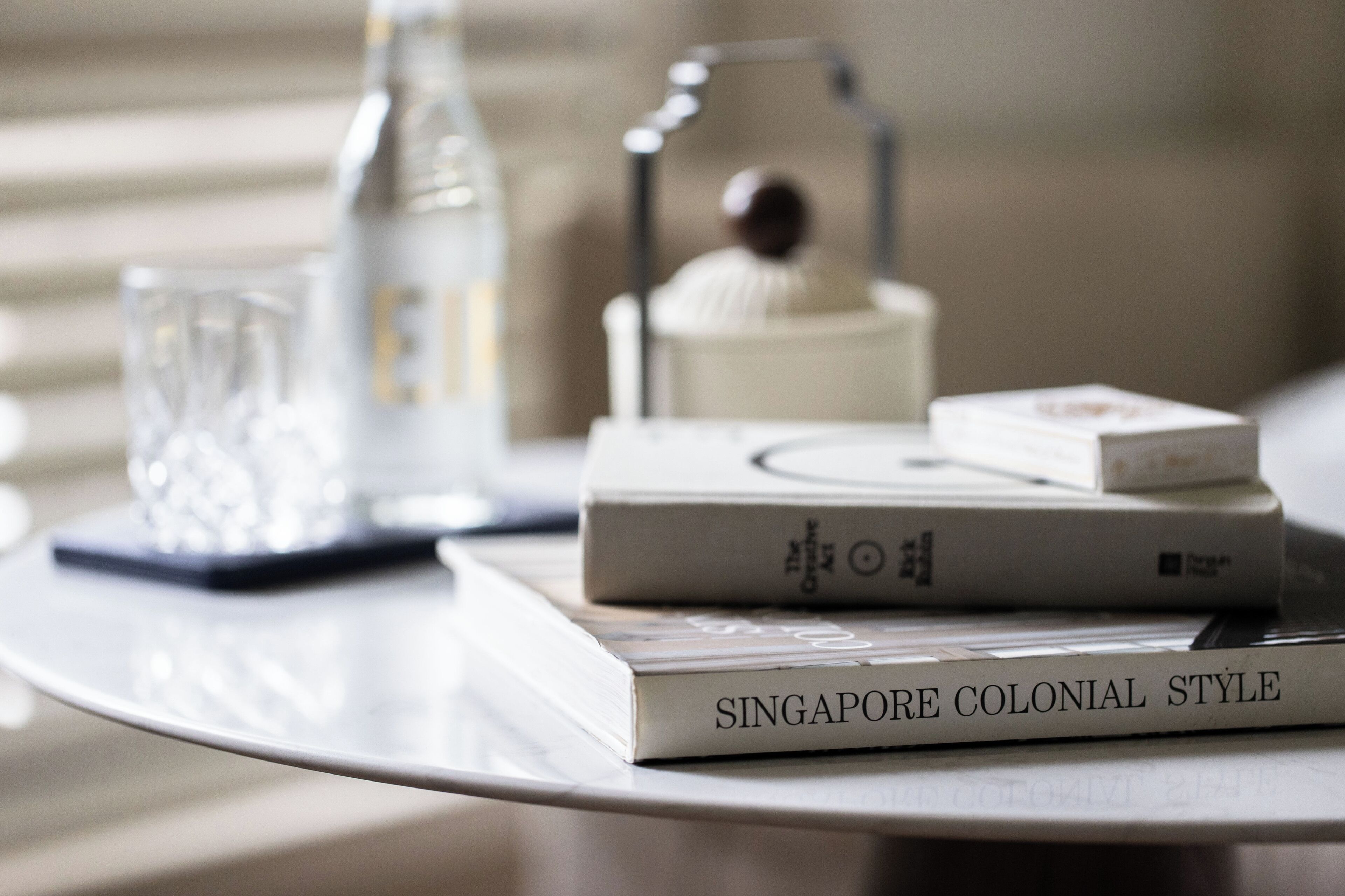 Una pila de libros sobre una mesa, incluyendo uno titulado 'SINGAPORE COLONIAL STYLE'.