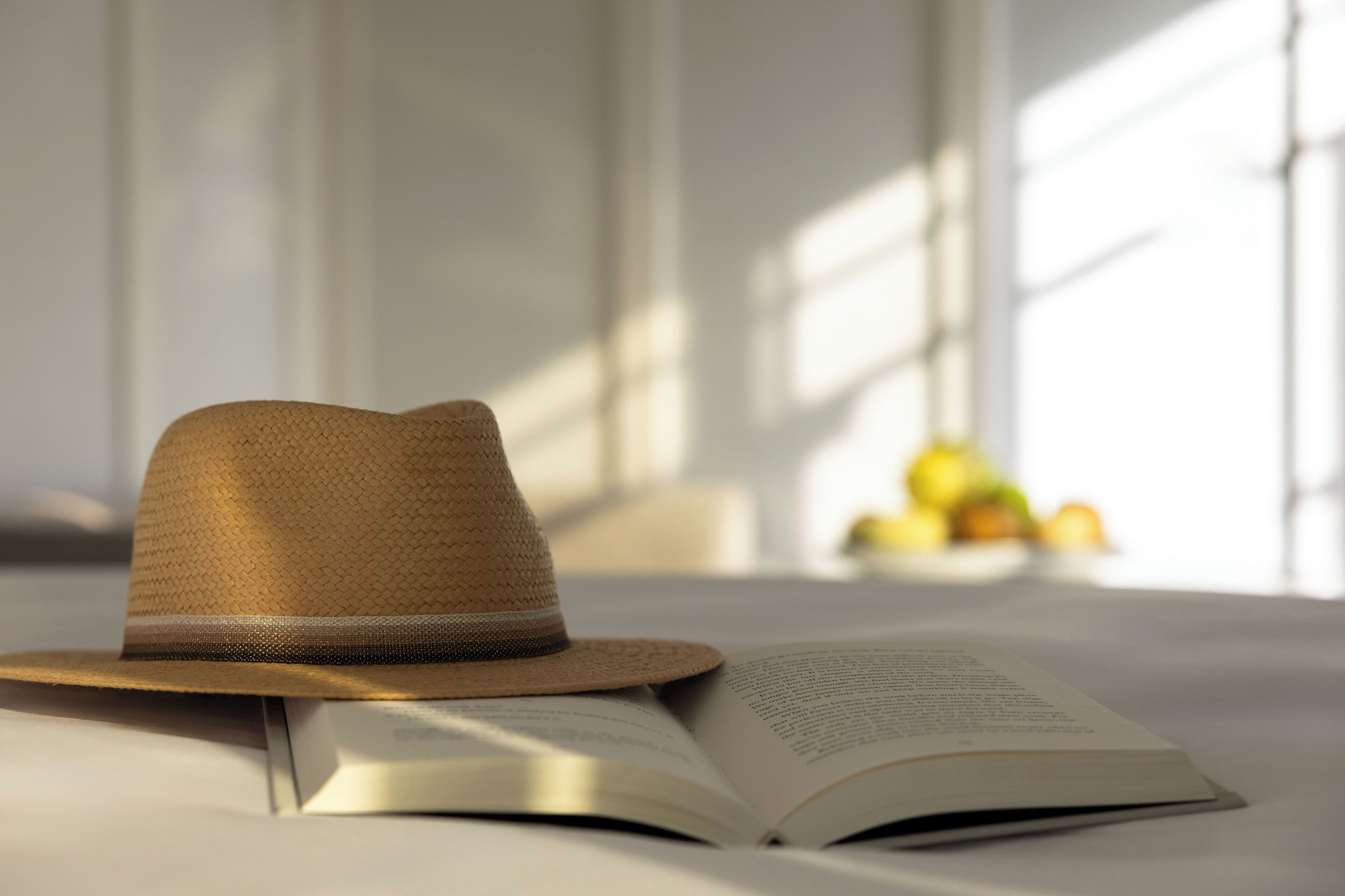 A hat on a bed with an open book beside it.