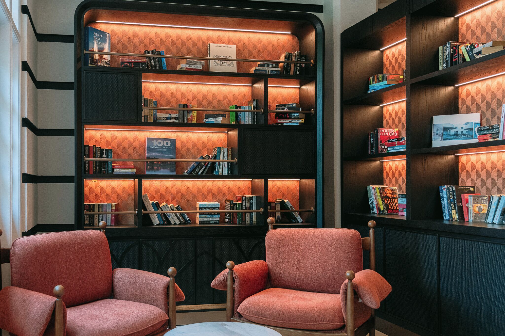 A library with bookshelves, two armchairs, and a small table.
