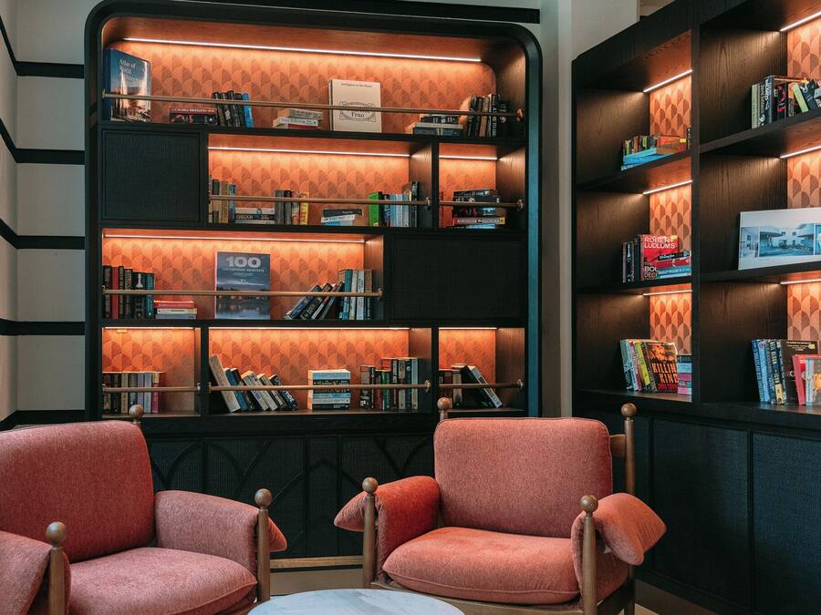 A library with bookshelves, two armchairs, and a small table.