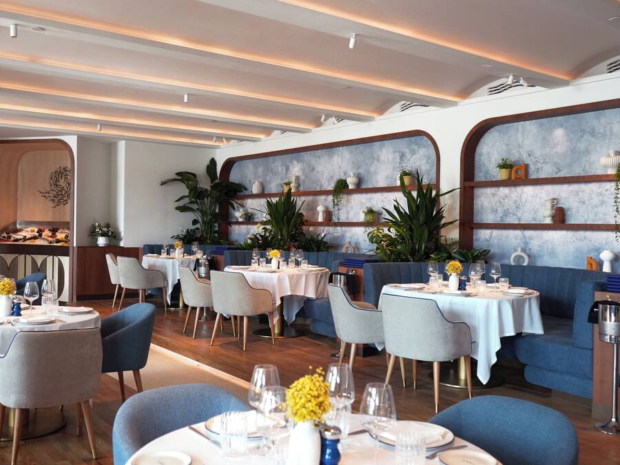 Un restaurant avec des tables rondes, des chaises et des étagères ornées de plantes.