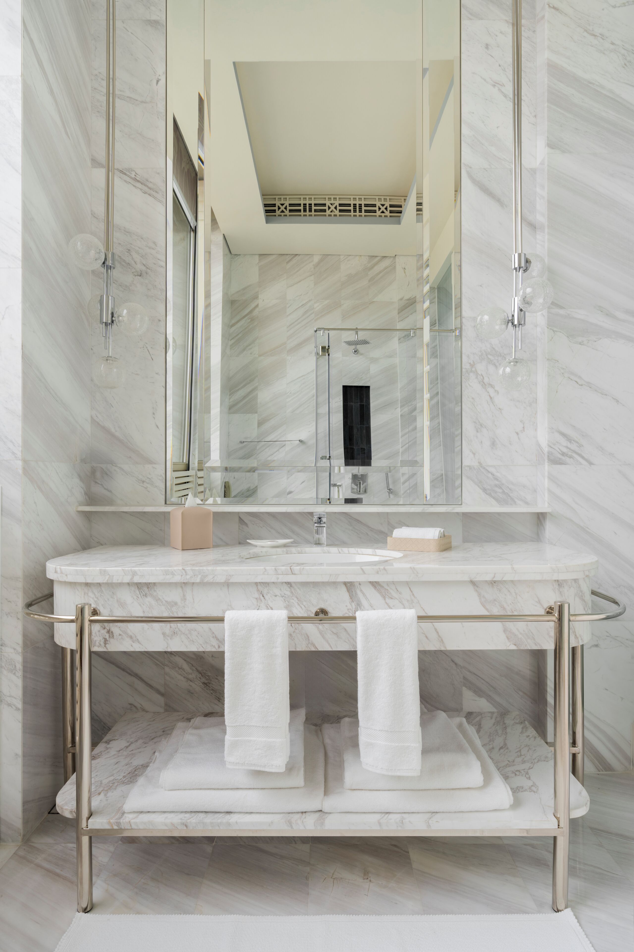 Une salle de bain moderne avec un meuble-lavabo en marbre, un grand miroir et une douche à parois de verre.