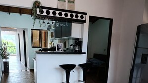A modern kitchen with a central island, bar stools, and a refrigerator. - Vista Hermosa Apartment In The Middle Of Medellin (Medellín)