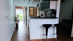 A modern kitchen with a central island, two bar stools, and a hanging plant. - Vista Hermosa Apartment In The Middle Of Medellin (Medellín)