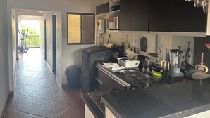 A kitchen with a black countertop, a microwave, and a sink. There is a window with a view of the outside. - Vista Hermosa Apartment In The Middle Of Medellin (Medellín)