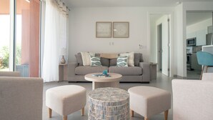A modern living room with a grey sofa, two ottomans, a coffee table, and a patterned side table.