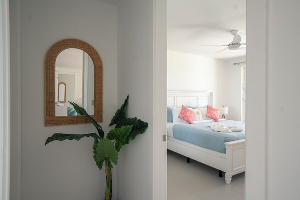 Un dormitorio con cama, ventilador de techo y un espejo grande en la pared.