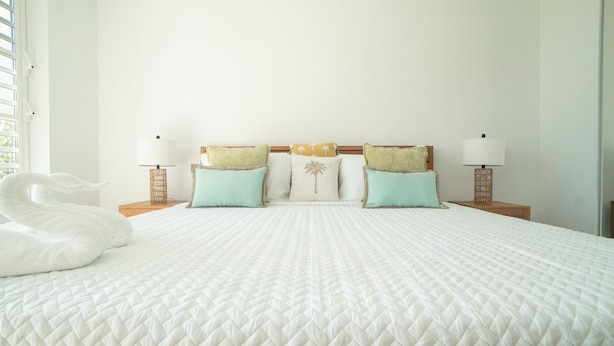 A neatly made bed with a quilted white duvet, two matching pillows, and a decorative swan.