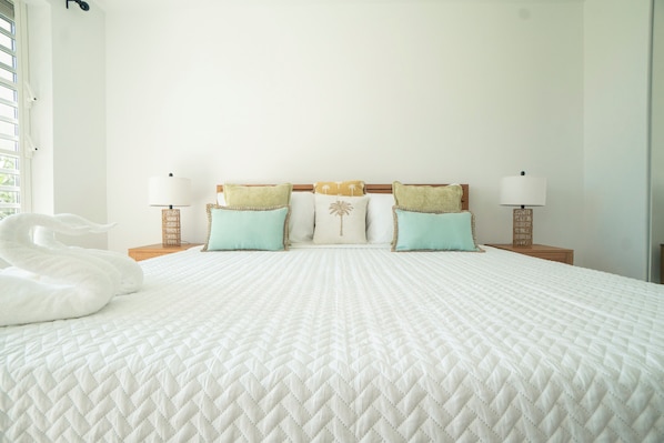 A neatly made bed with a quilted white duvet, two matching pillows, and a decorative swan.