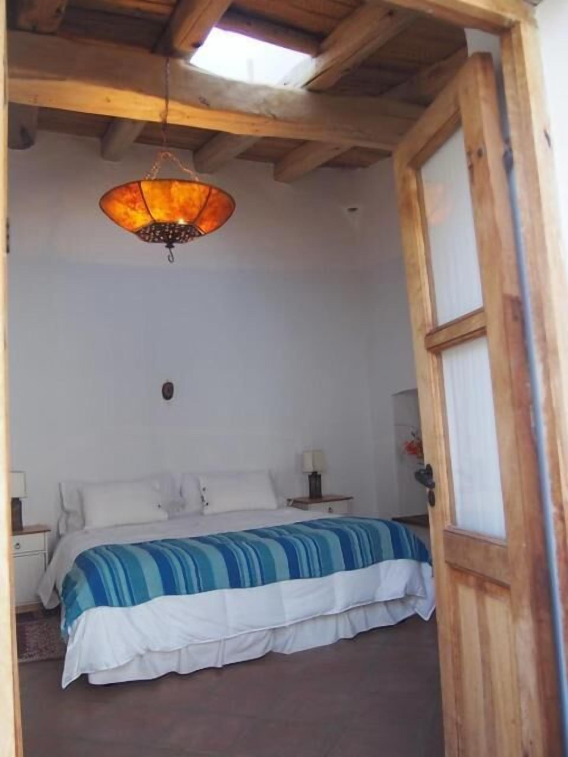 Un dormitorio con cama, mesita de noche, lámpara y una lámpara colgante.