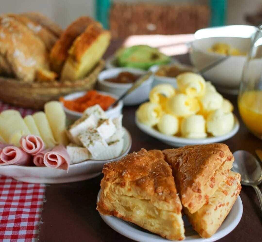 A table with various food items including pastries, cheese, and a bowl of fruit.