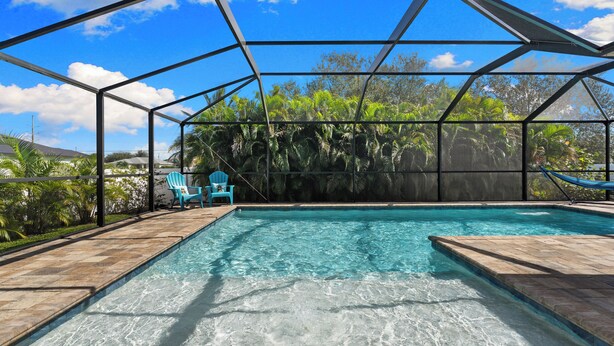 Piscina interna com água azul cristalina, cercada por estrutura metálica e vista para vegetação exuberante.