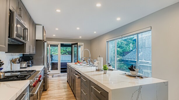 A modern kitchen with stainless steel appliances, a marble island, and large windows offering a view of the outdoors. - Mountain Luxury In Old Town Spa - Walk To Main 440 3 Bedroom Home (Park City)