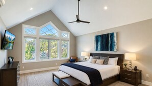A bedroom with a large bed, two bedside tables, a ceiling fan, and a view of trees through large windows. - Mountain Luxury In Old Town Spa - Walk To Main 440 3 Bedroom Home (Park City)