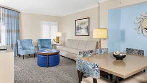 A hotel room with a sofa, two armchairs, a coffee table, a dining table with chairs, a ceiling fan, and a wall-mounted lamp. - Marriott 2-bedroom villa with AC, fitness room in welcoming Hilton Head Island (Hilton Head Island)