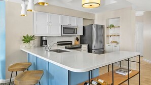 A modern kitchen with white cabinets, stainless steel appliances, and a central island with bar stools. - Marriott 2-bedroom villa with AC, fitness room in welcoming Hilton Head Island (Hilton Head Island)