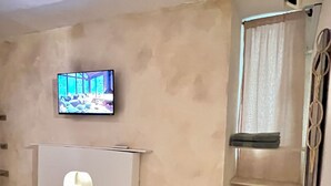 A reception area with a flat-screen TV mounted on the wall, a white reception desk, a small potted plant, and a window with curtains. - Monet apartment-studio. Tranquility, style and location.  (Santa Marta)