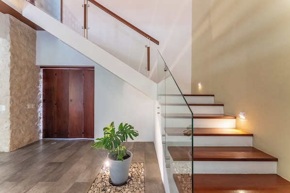 Eine moderne Treppe mit Holzstufen und Glasgeländern, die zu einer zweiten Etage führt.