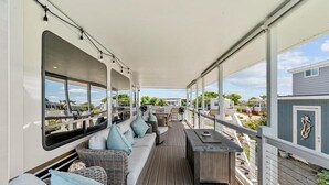 Eine überdachte Terrasse im Freien mit einer Sitzecke, Sesseln und einem Tisch.