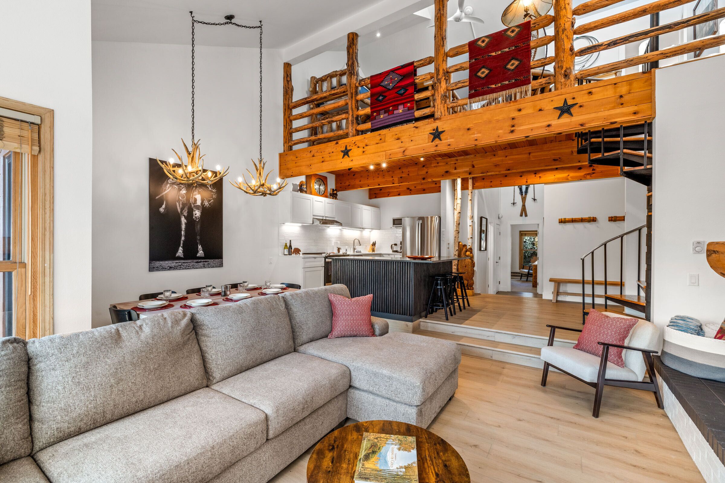 En modern inredning med ett matområde, en soffa, ett soffbord och en trappa som leder upp till en övre våning.