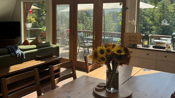 Ein gemütlicher Essbereich mit Holztisch, Stühlen und einer Vase mit Sonnenblumen.