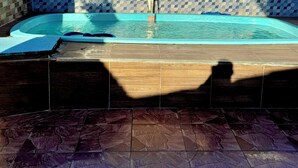 Ein Schwimmbecken mit einer Fliesenwand und einer Holzterrasse.
