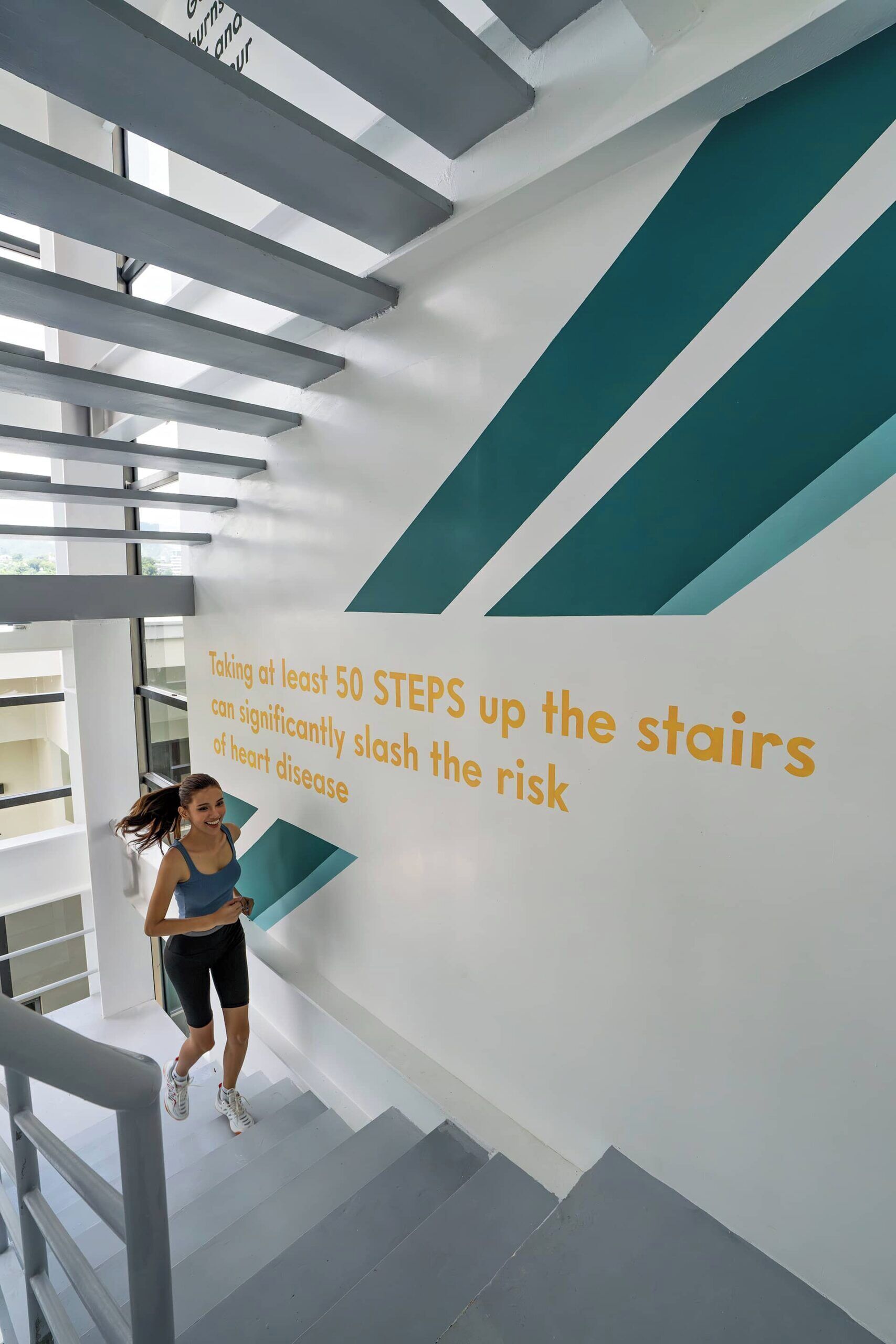 Una persona corriendo por una escalera con un mensaje motivacional en la pared.
