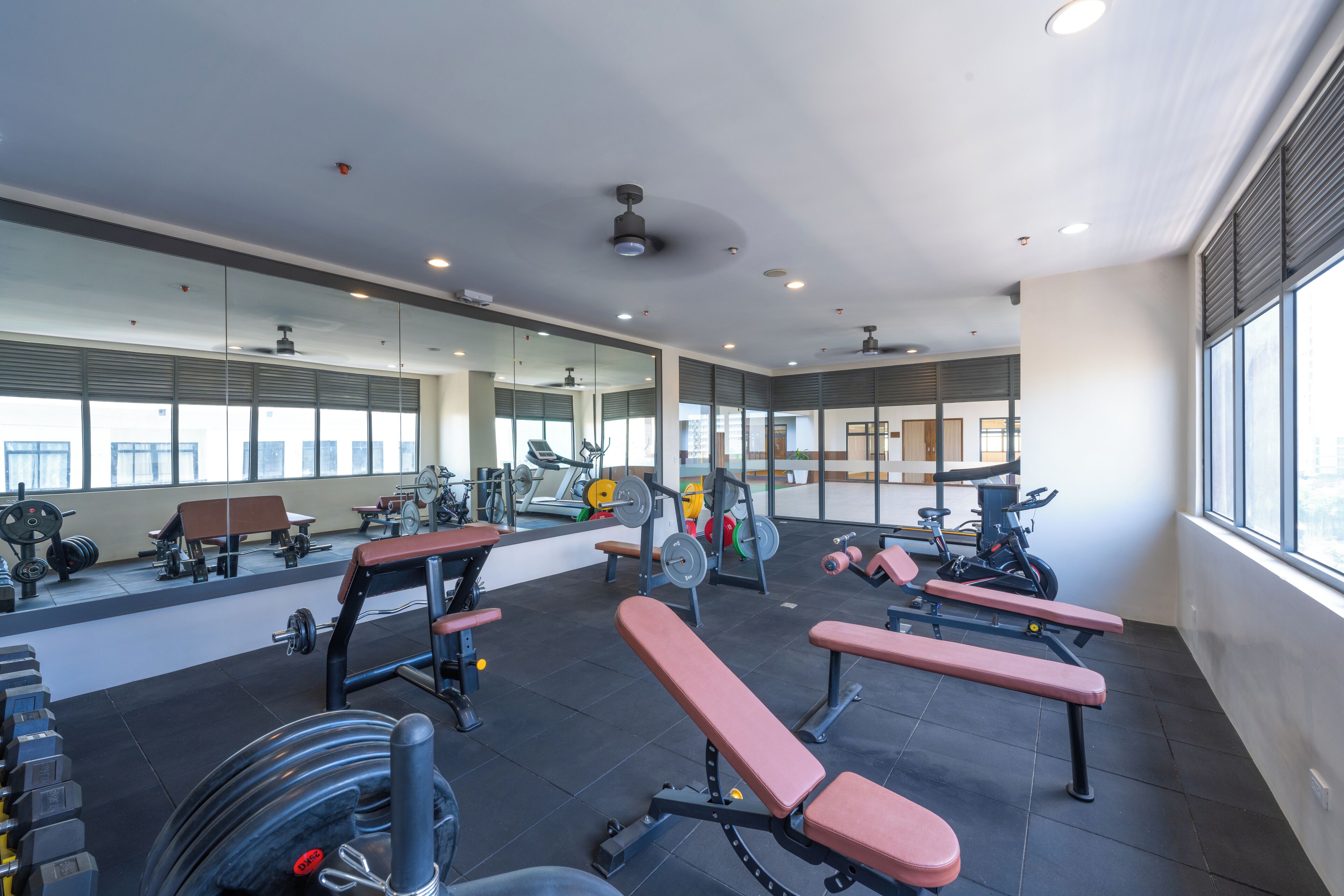 A gym with exercise equipment, benches, and a large mirror.