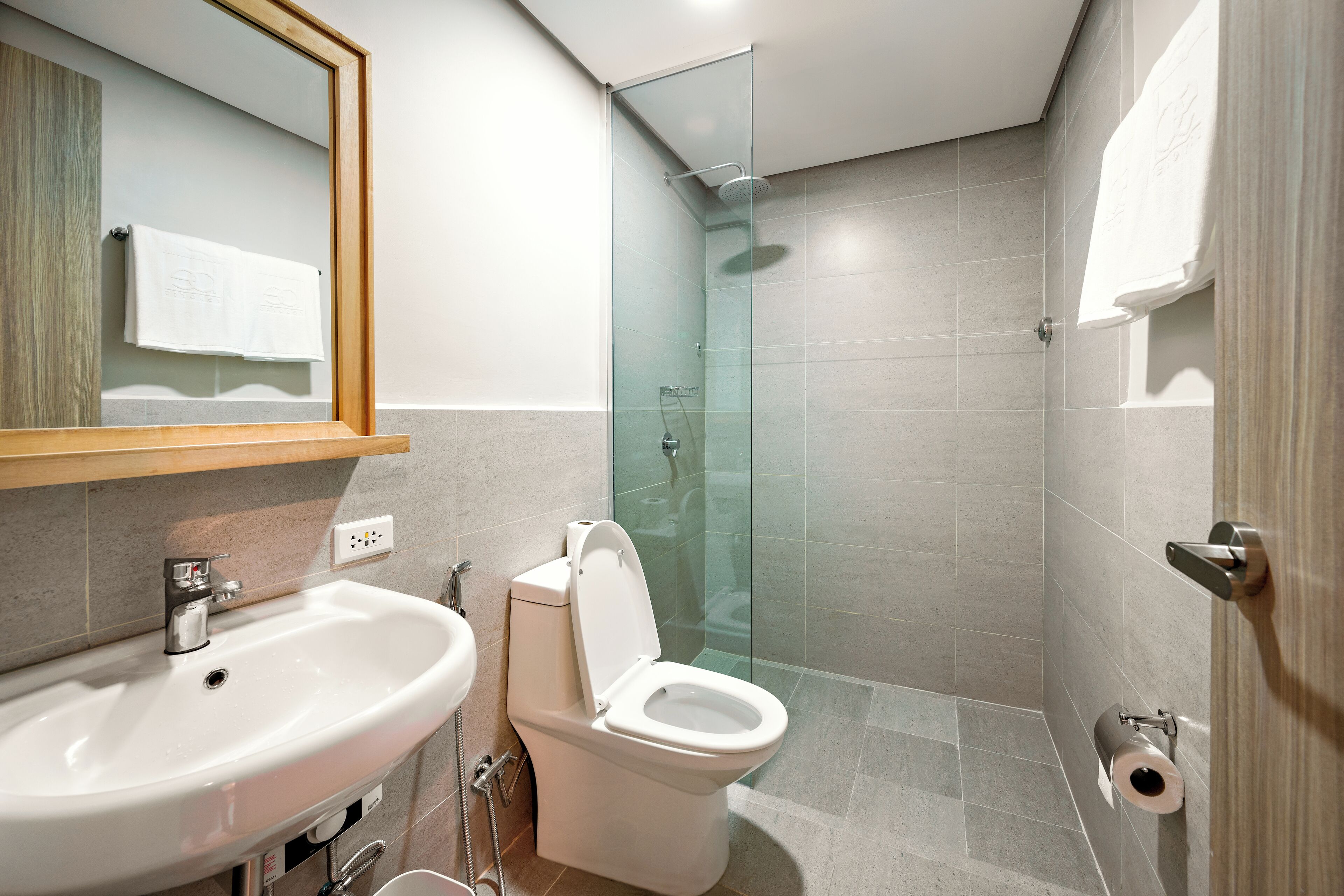 Ein modernes Badezimmer mit Duschkabine aus Glas, einem weißen Waschbecken und einer Toilette.
