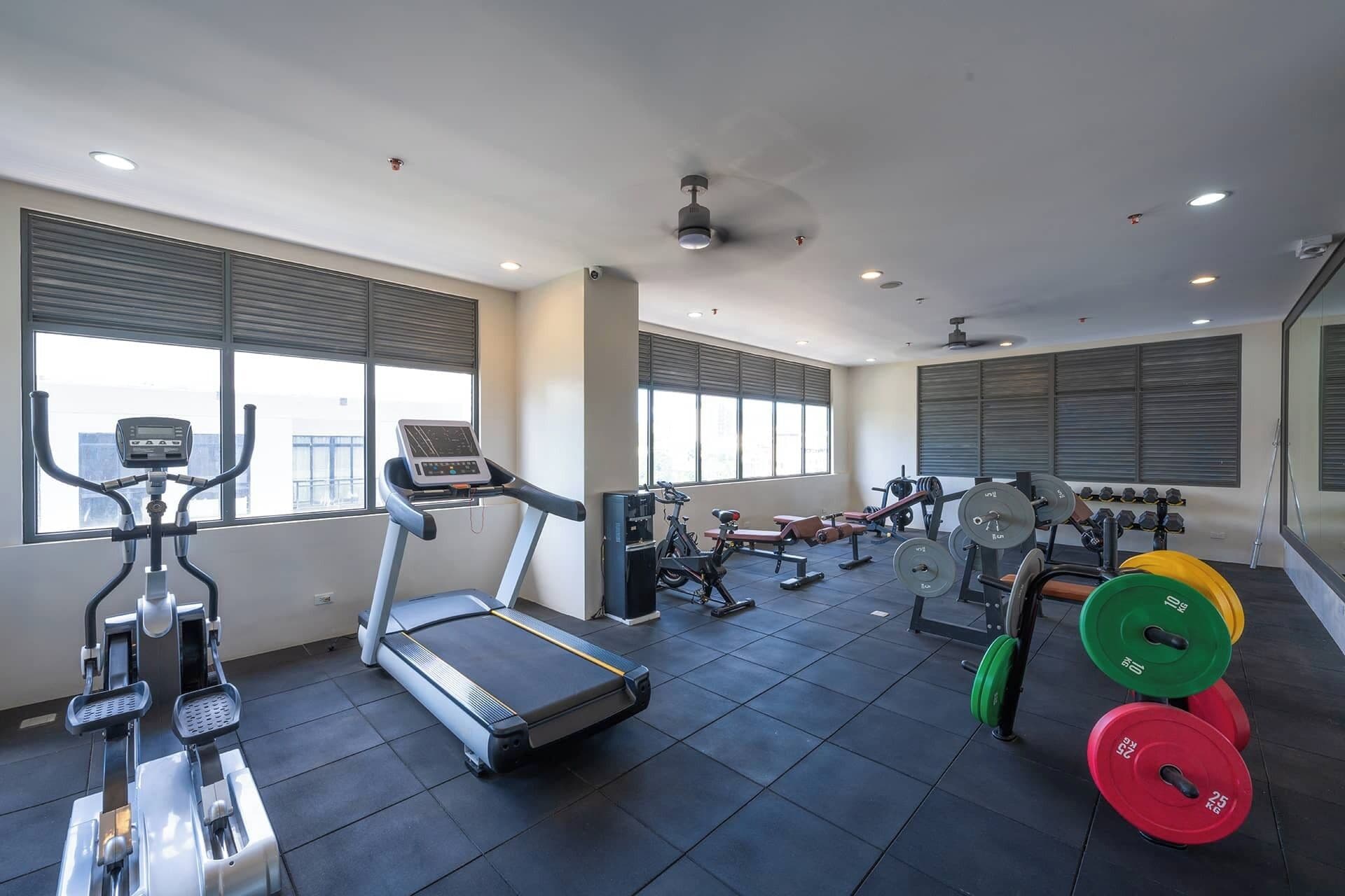 A gym with treadmills, elliptical machines, weight benches, and free weights.
