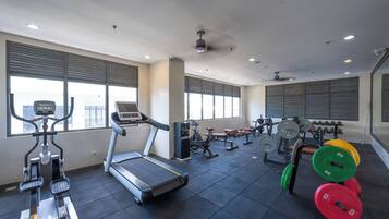 Une salle de sport équipée de tapis de course, de vélos elliptiques, de bancs de musculation et de poids libres.