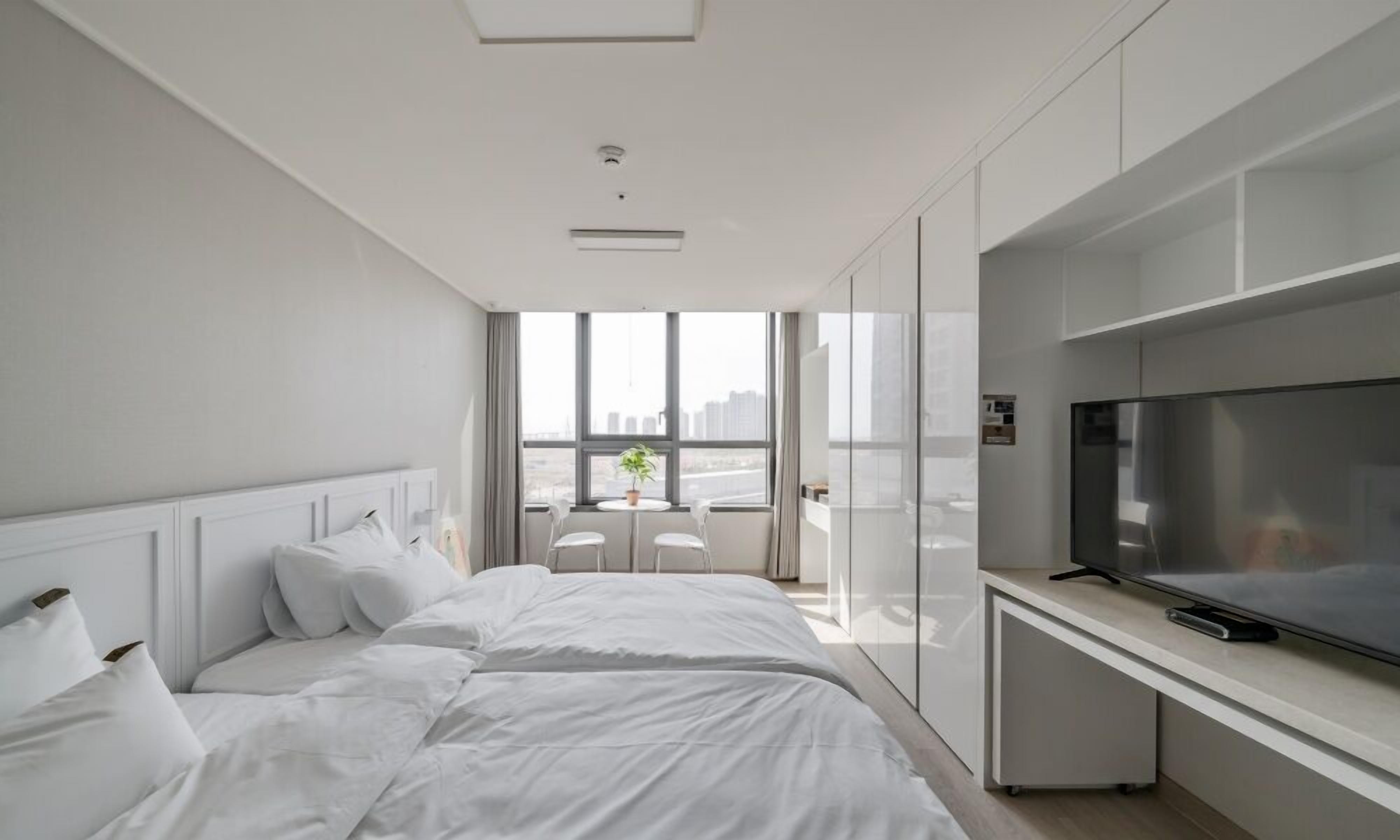 A modern hotel room with a large bed, a TV, and a city view.