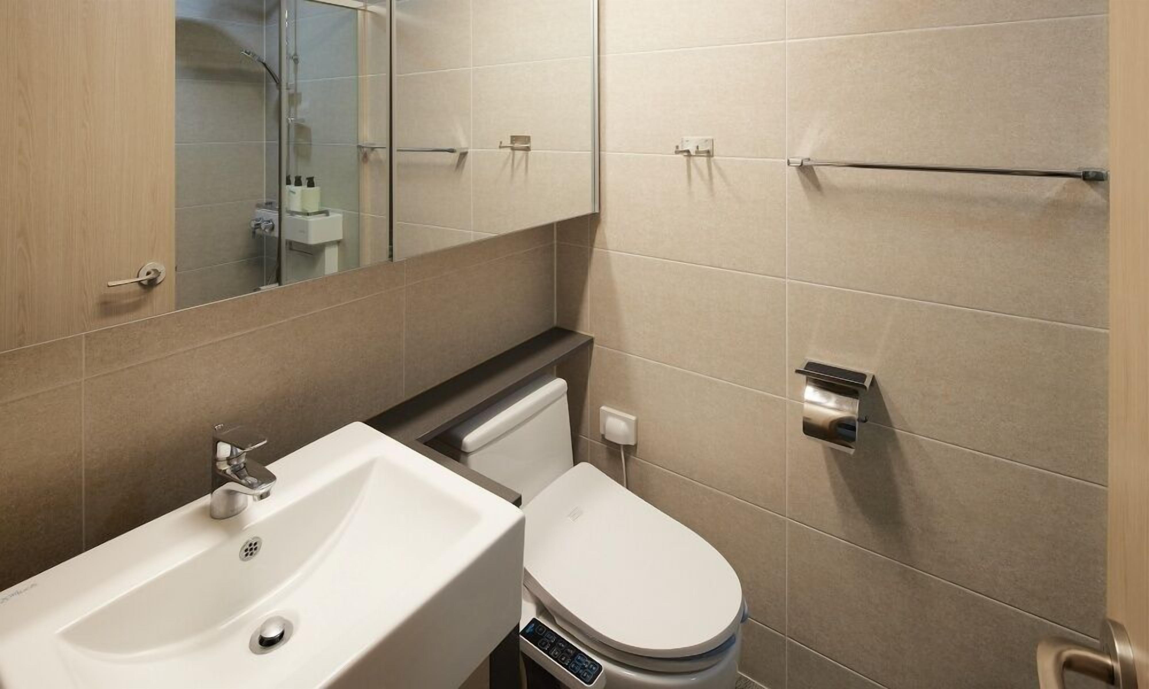 Un baño moderno con lavamanos, inodoro y cabina de ducha de vidrio.