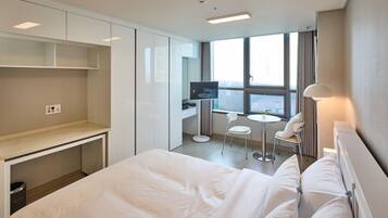 Habitación de hotel moderna con una cama grande, un escritorio, un televisor y una pequeña mesa con sillas.