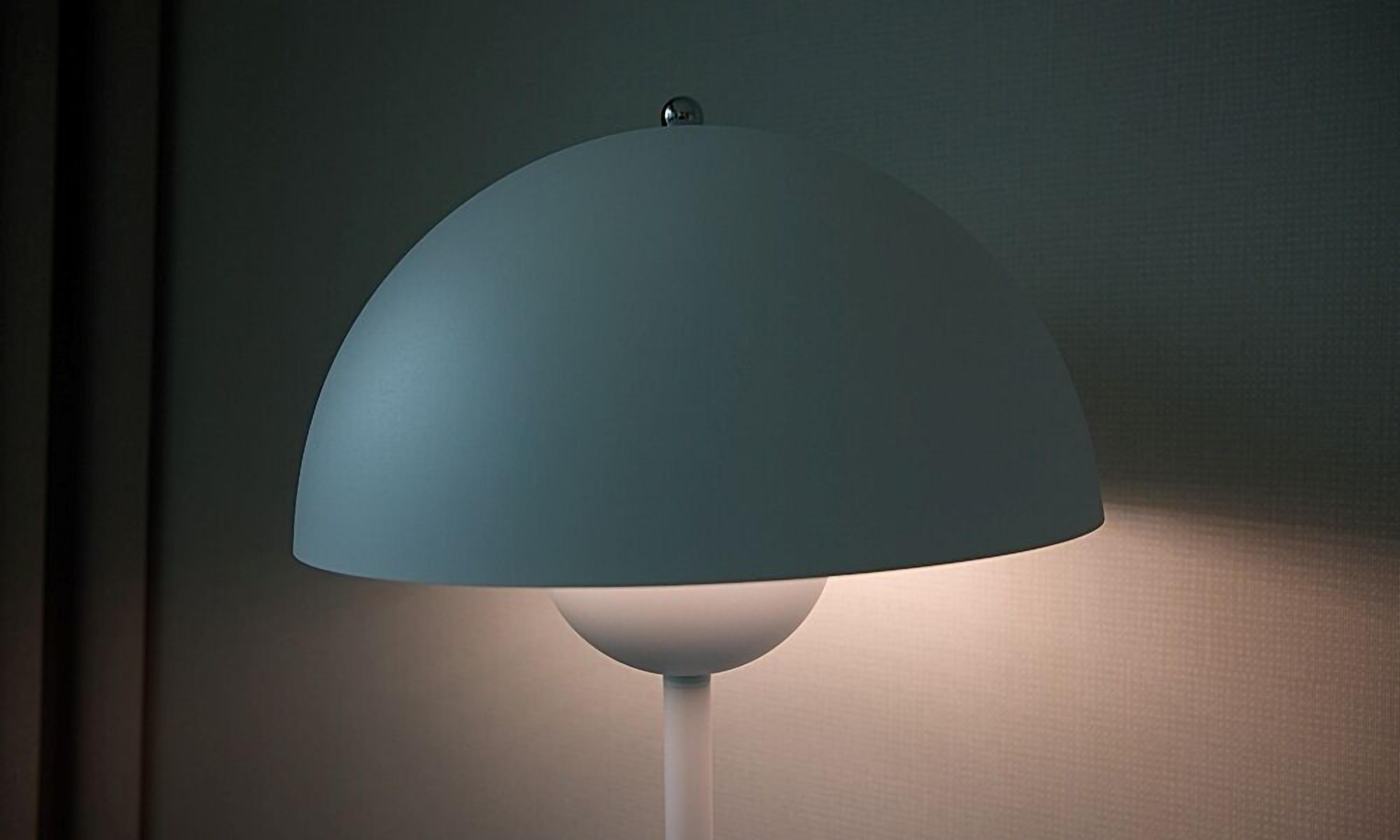 Eine Lampe mit weißem Fuß und blauem Lampenschirm.